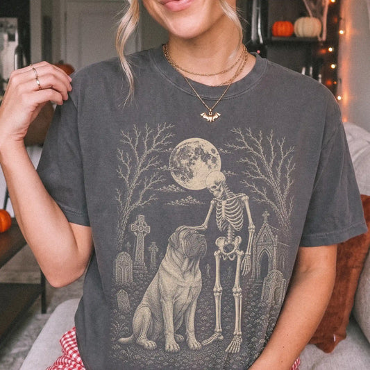 Model wearing a Pepper Comfort Colors® T-shirt showing Mastiff sharing a quiet cemetery moment with a friendly skeleton