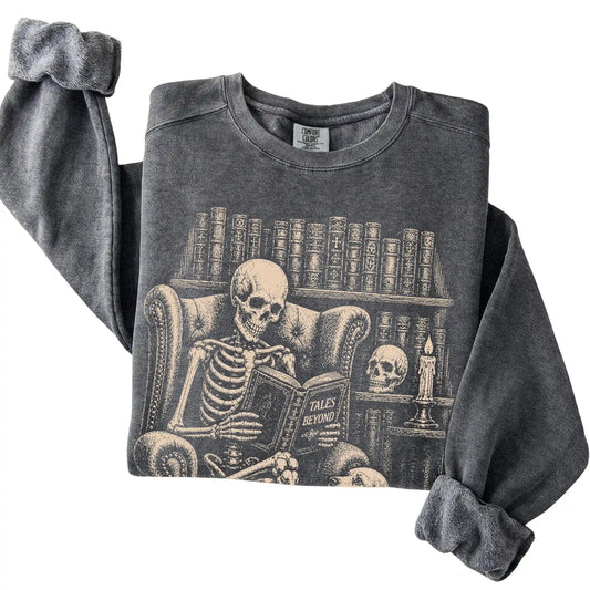 Folded Pepper sweatshirt with a skeleton reading Tales Beyond to a Cocker Spaniel