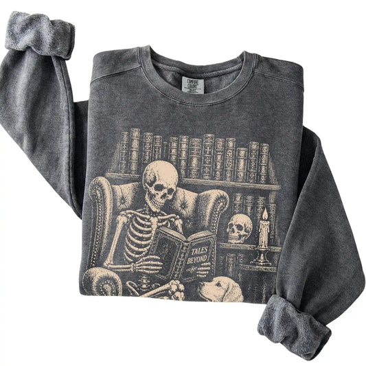 Folded Pepper sweatshirt with a skeleton reading Tales Beyond to a Golden Retriever