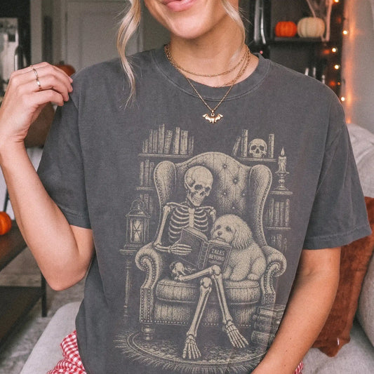 Model wearing a Pepper Comfort Colors® T-shirt showing skeleton reading in a library beside a Havanese