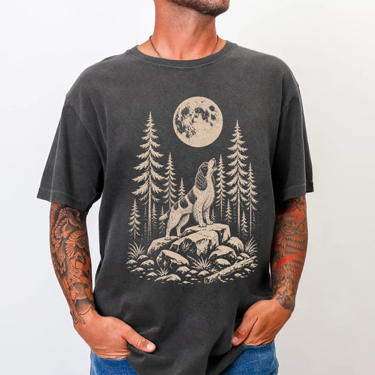 Model wearing a Pepper Comfort Colors® T-shirt with a Springer Spaniel howling beneath the moon and pine trees
