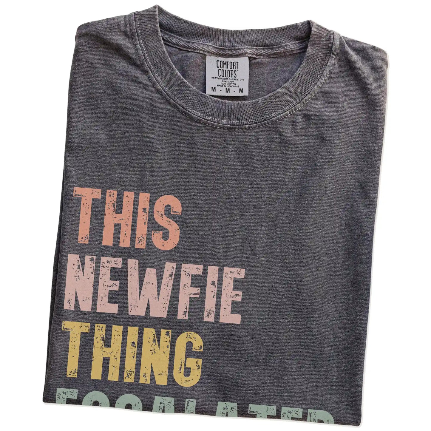 Folded Pepper Comfort Colors® T-shirt showing retro “This Newfie Thing Escalated Quickly” lettering