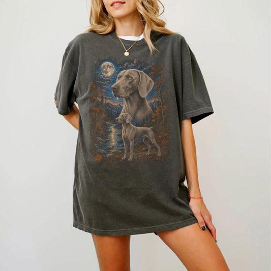 Model wearing a Pepper Comfort Colors® t-shirt featuring Weimaraner in a moonlit fall forest