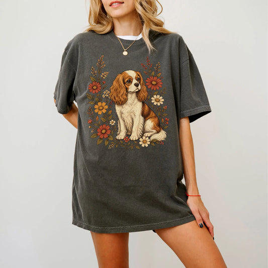 Model wearing a Pepper Comfort Colors® T-shirt showing Cavalier King Charles Spaniel portrait surrounded by wildflowers benea