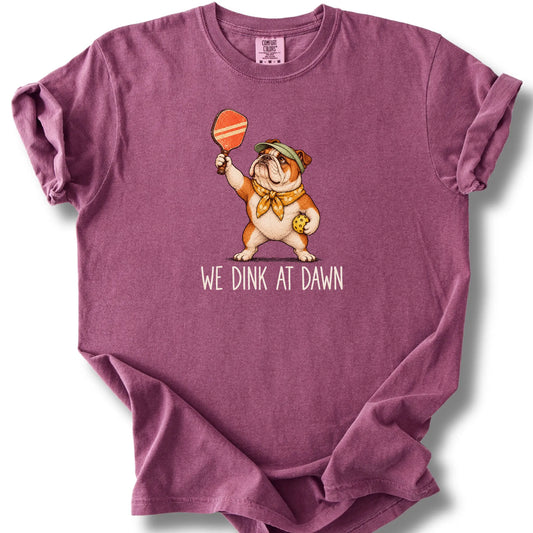 Bulldog with a pickleball paddle and ball on a Berry Comfort Colors® T-shirt with We Dink at Dawn text