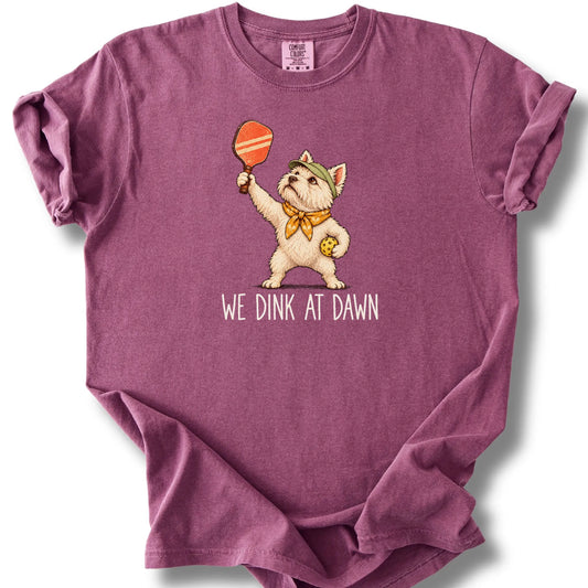 Westie with a pickleball paddle and ball on a Berry Comfort Colors® T-shirt with We Dink at Dawn text