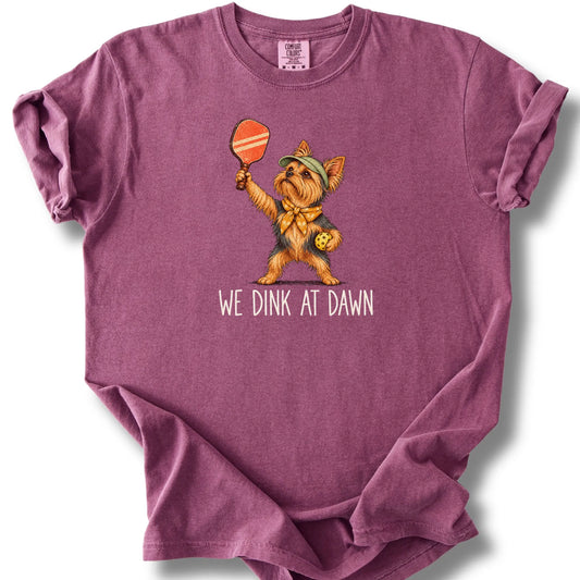 Yorkie with a pickleball paddle and ball on a Berry Comfort Colors® T-shirt with We Dink at Dawn text