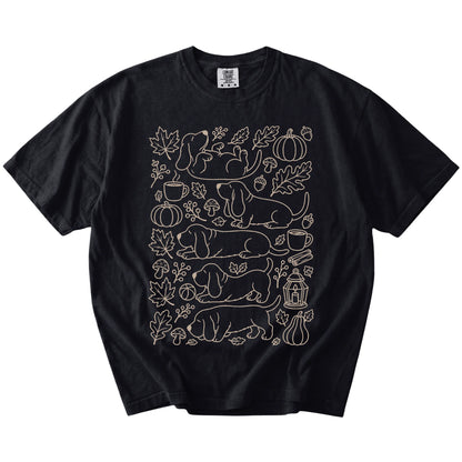 Basset Hound dogs with pumpkins, leaves, acorns, and woodland details on a Black Comfort Colors® T-shirt