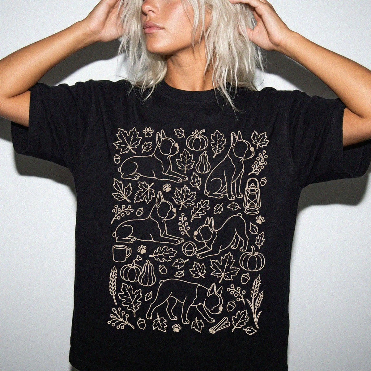 Model wearing a Black Comfort Colors® T-shirt with Boston Terrier dogs with pumpkins, leaves, acorns, and woodland details