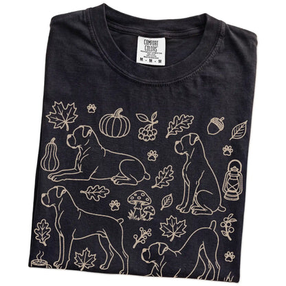 Folded Black Comfort Colors® T-shirt showing Boxer dogs with pumpkins, leaves, acorns, and woodland details