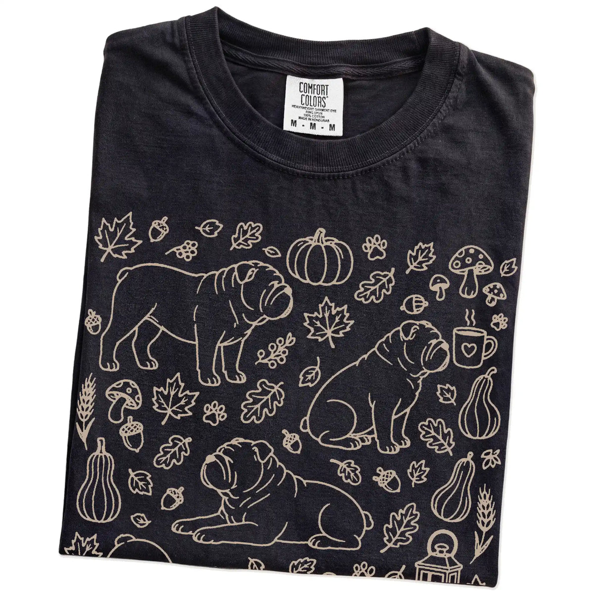 Folded Black Comfort Colors® T-shirt showing Bulldog dogs with pumpkins, leaves, acorns, and woodland details
