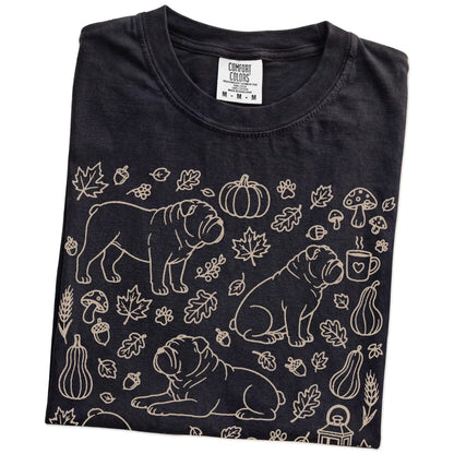 Folded Black Comfort Colors® T-shirt showing Bulldog dogs with pumpkins, leaves, acorns, and woodland details