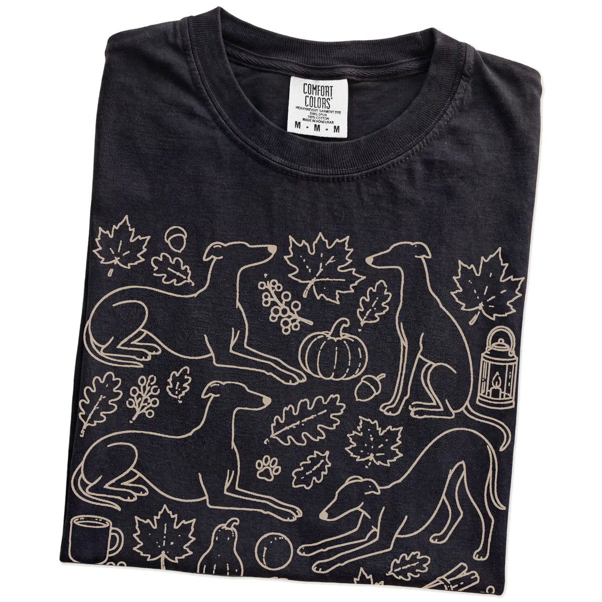 Folded Black Comfort Colors® T-shirt showing Greyhound dogs with pumpkins, leaves, acorns, and woodland details