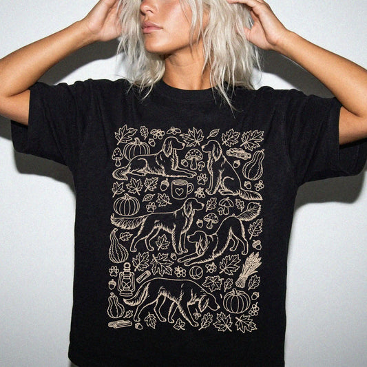 Model wearing a Black Comfort Colors® T-shirt with Irish Setter dogs with pumpkins, leaves, acorns, and woodland details