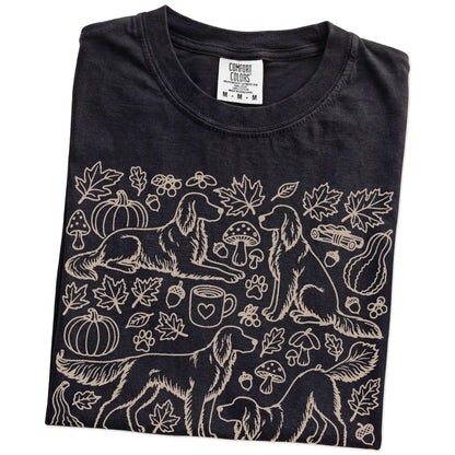 Folded Black Comfort Colors® T-shirt showing Irish Setter dogs with pumpkins, leaves, acorns, and woodland details