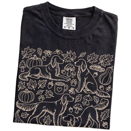 Folded Black Comfort Colors® T-shirt showing Irish Setter dogs with pumpkins, leaves, acorns, and woodland details