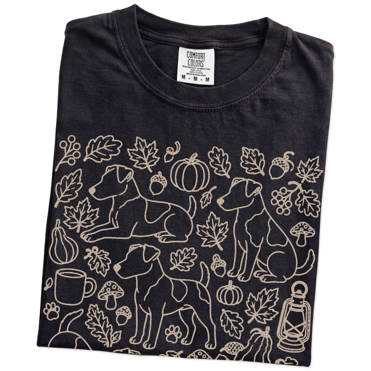 Folded Black Comfort Colors® T-shirt showing Jack Russell dogs with pumpkins, leaves, acorns, and woodland details