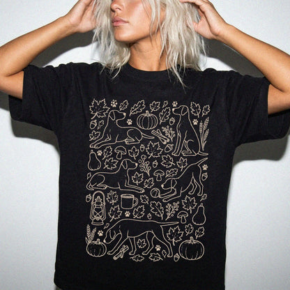 Model wearing a Black Comfort Colors® T-shirt with Pointer dogs with pumpkins, leaves, acorns, and woodland details