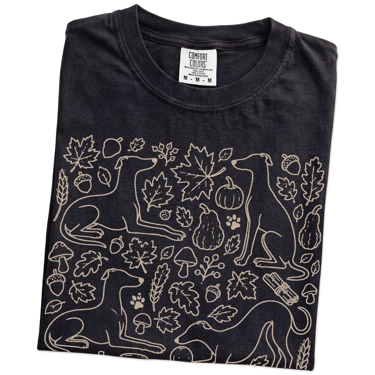 Folded Black Comfort Colors® T-shirt showing Whippet dogs with pumpkins, leaves, acorns, and woodland details