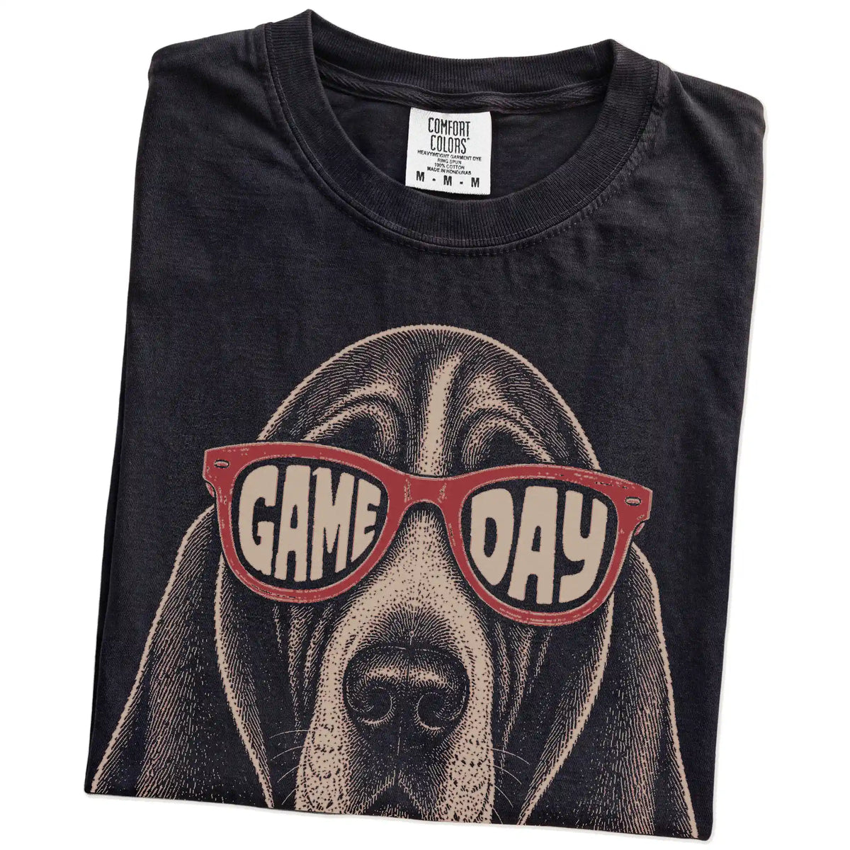 Folded Black Comfort Colors® T-shirt showing basset hound wearing red game day sunglasses