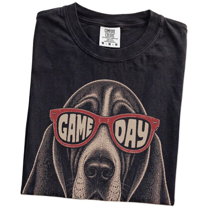 Folded Black Comfort Colors® T-shirt showing basset hound wearing red game day sunglasses