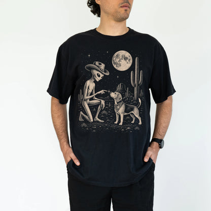 Model wearing a Black Comfort Colors® T-shirt with cowboy alien fist-bumping a beagle beneath the moon