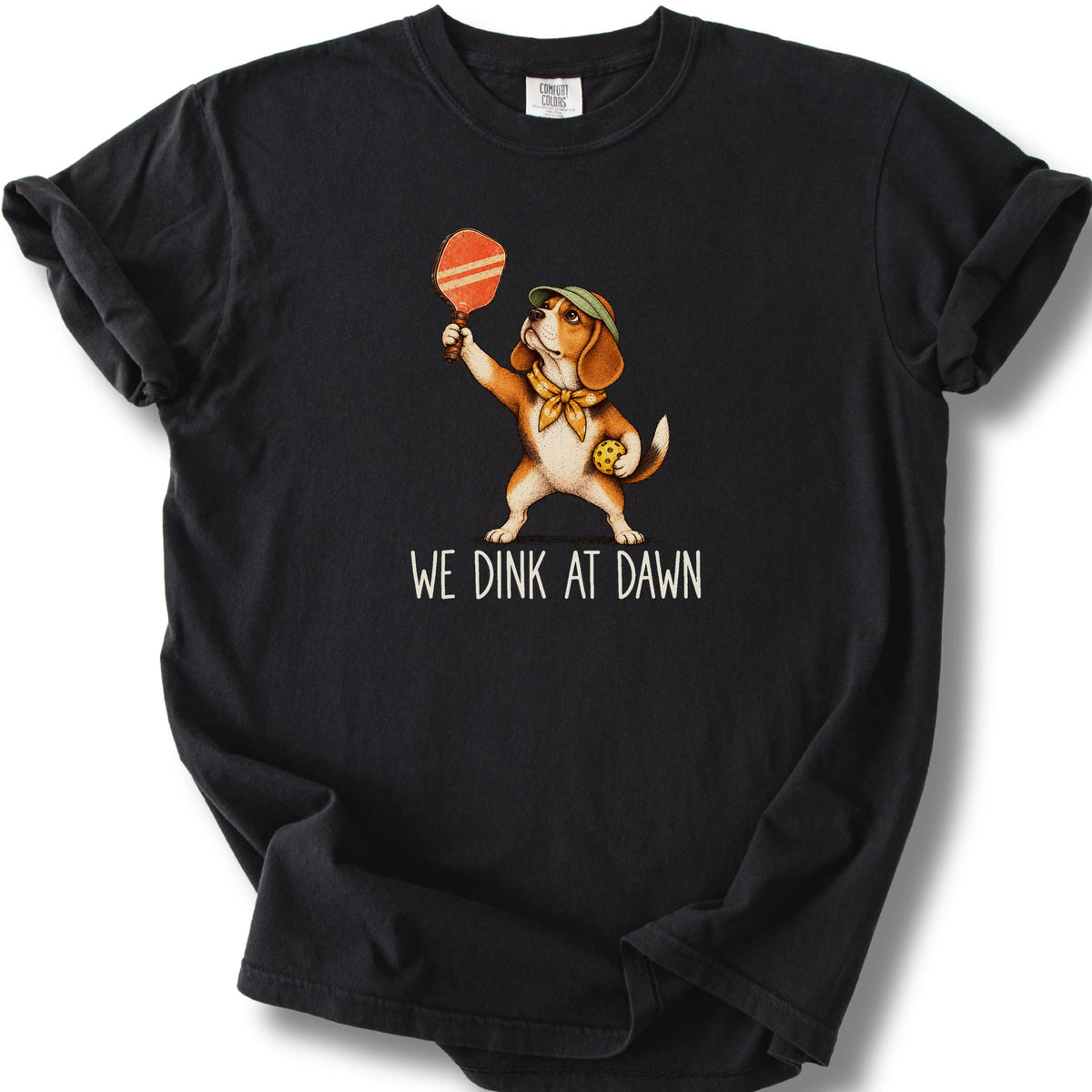 Beagle with a pickleball paddle and ball on a Black Comfort Colors® T-shirt with We Dink at Dawn text
