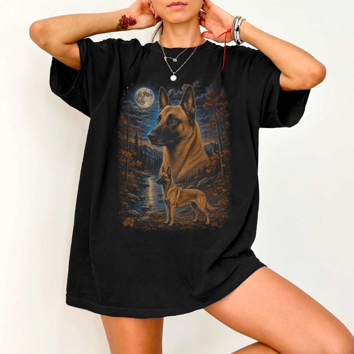 Model wearing a Black Comfort Colors® t-shirt featuring Belgian Malinois in a moonlit fall forest