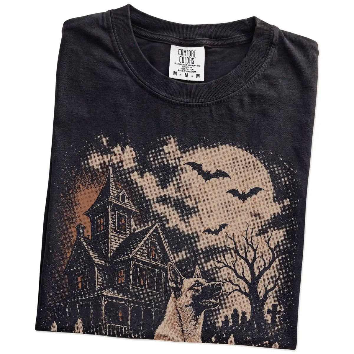 Folded Black Comfort Colors® T-shirt showing Belgian Malinois in a vintage haunted-house scene