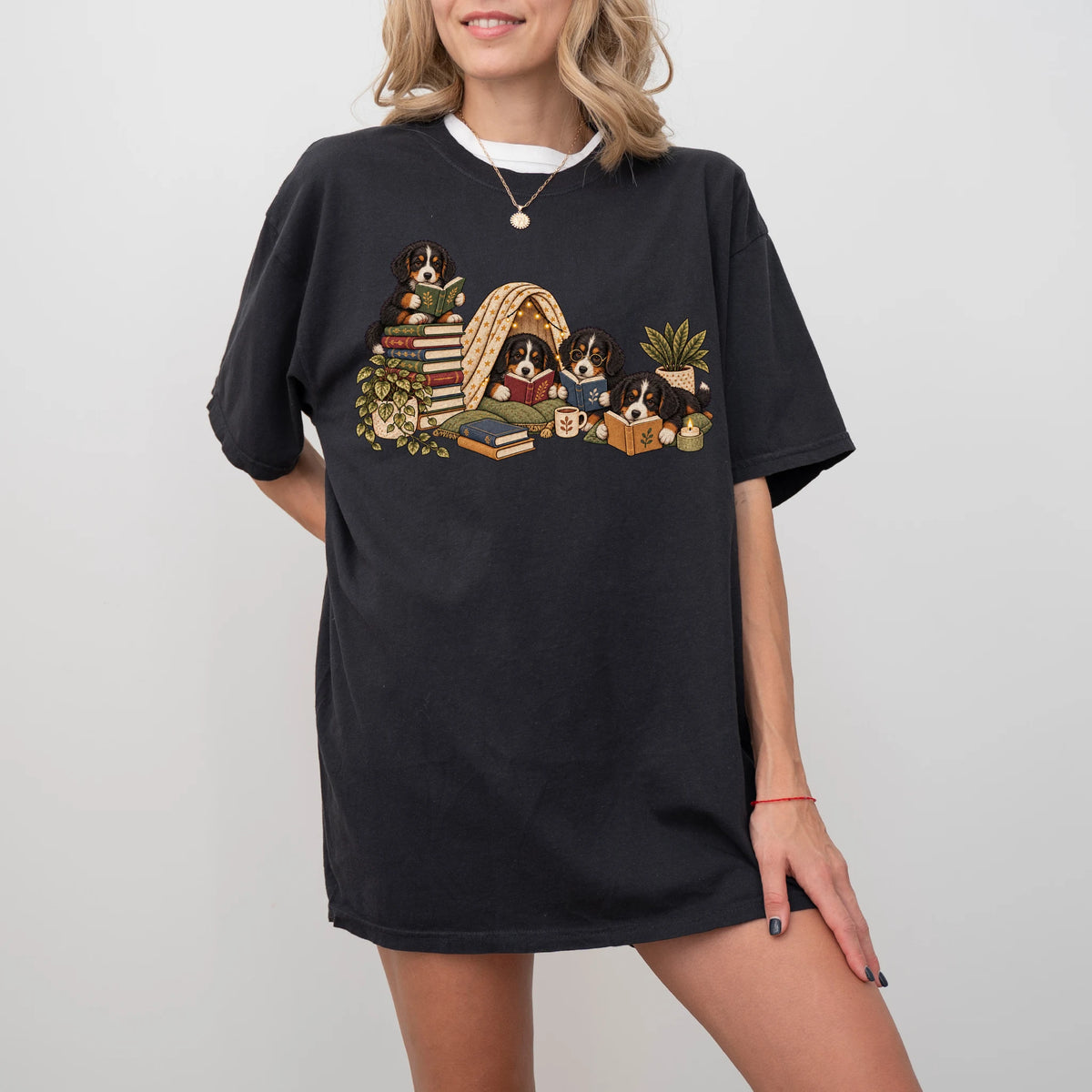 Bernese Mountain Dog puppies reading books in a cozy blanket fort on a Black T-shirt worn by a model