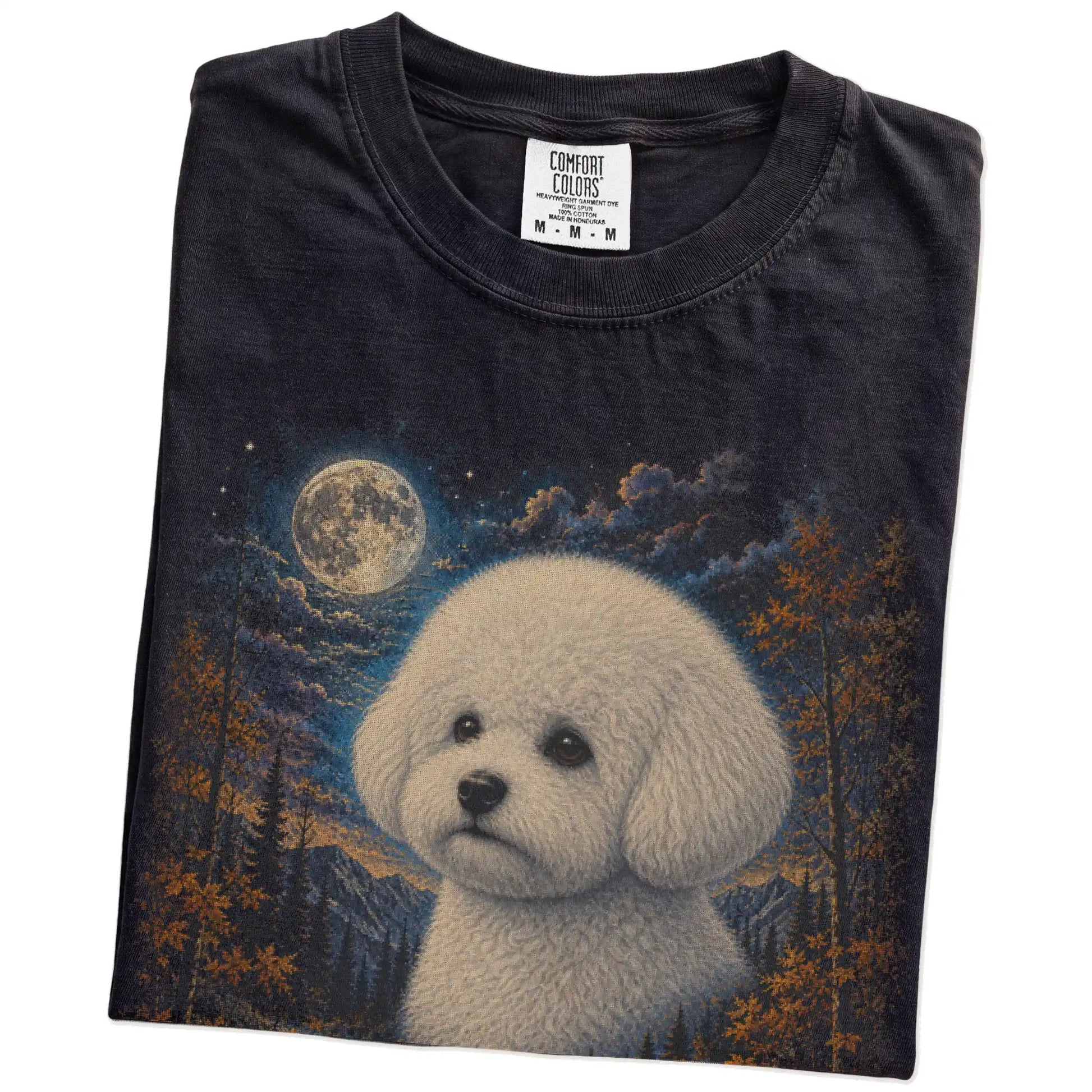 Folded Black Comfort Colors® t-shirt showing Bichon Frise in a fall forest graphic