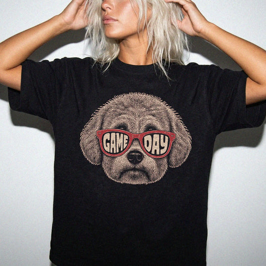 Model wearing a Black Comfort Colors® T-shirt with bichon frise wearing red game day sunglasses