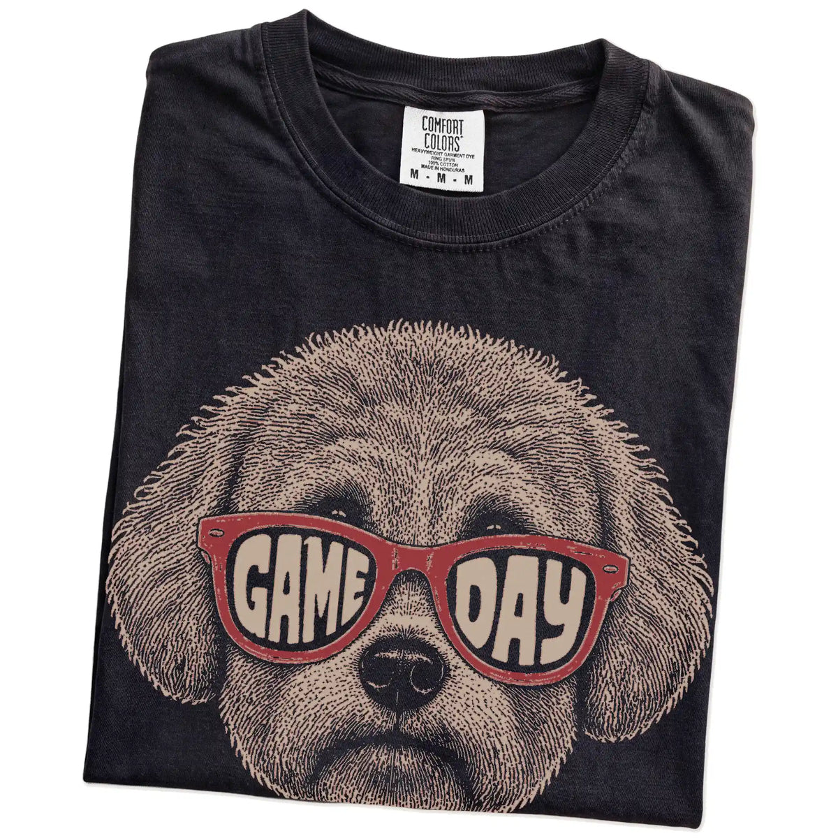 Folded Black Comfort Colors® T-shirt showing bichon frise wearing red game day sunglasses