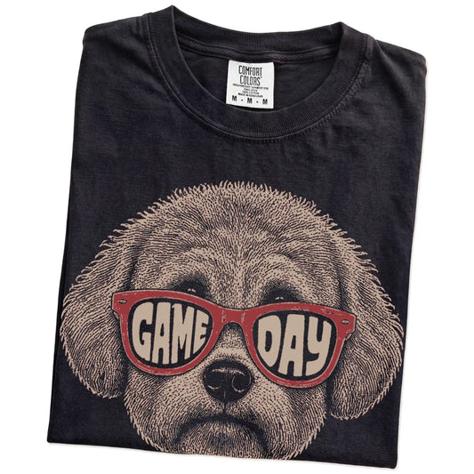 Folded Black Comfort Colors® T-shirt showing bichon frise wearing red game day sunglasses