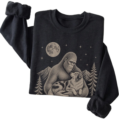 Folded Black crewneck sweatshirt showing Bigfoot holding an Australian Shepherd