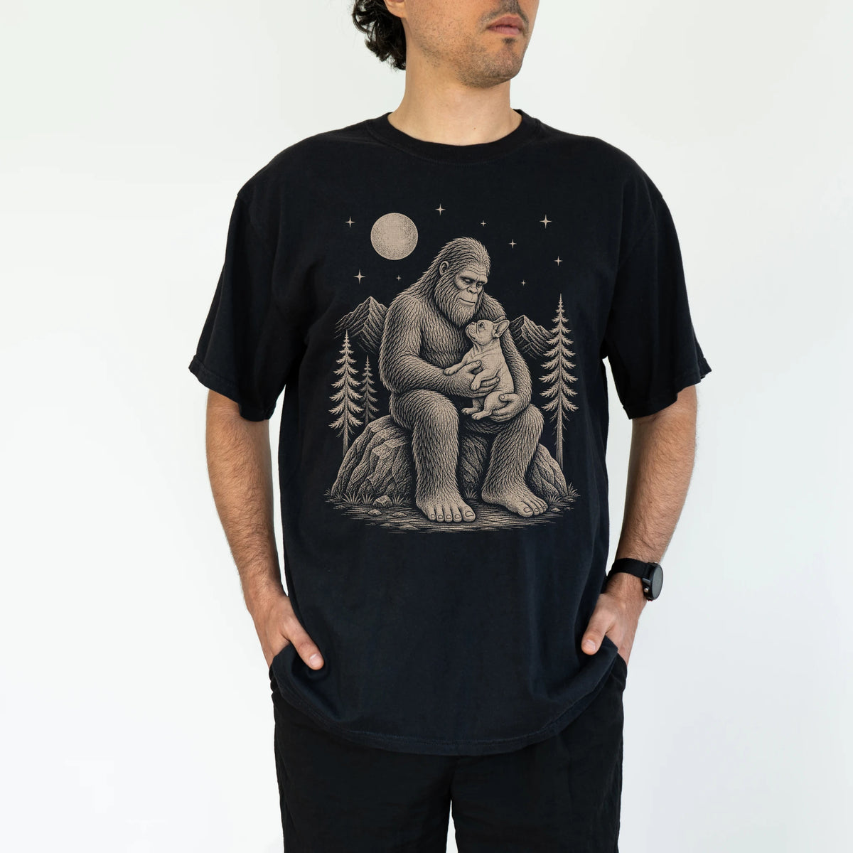 Model wearing a Black Comfort Colors® T-shirt showing Bigfoot holding a French Bulldog