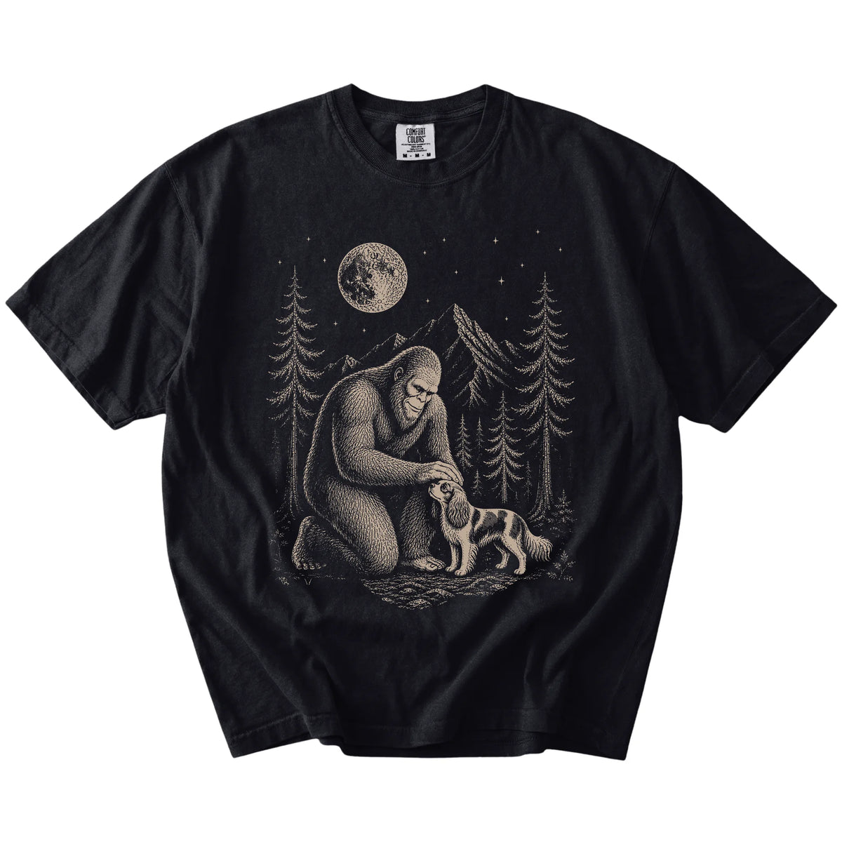 Bigfoot petting a Cavalier King Charles Spaniel beneath the moon in a pine forest on a Black Comfort Colors® T-shirt
