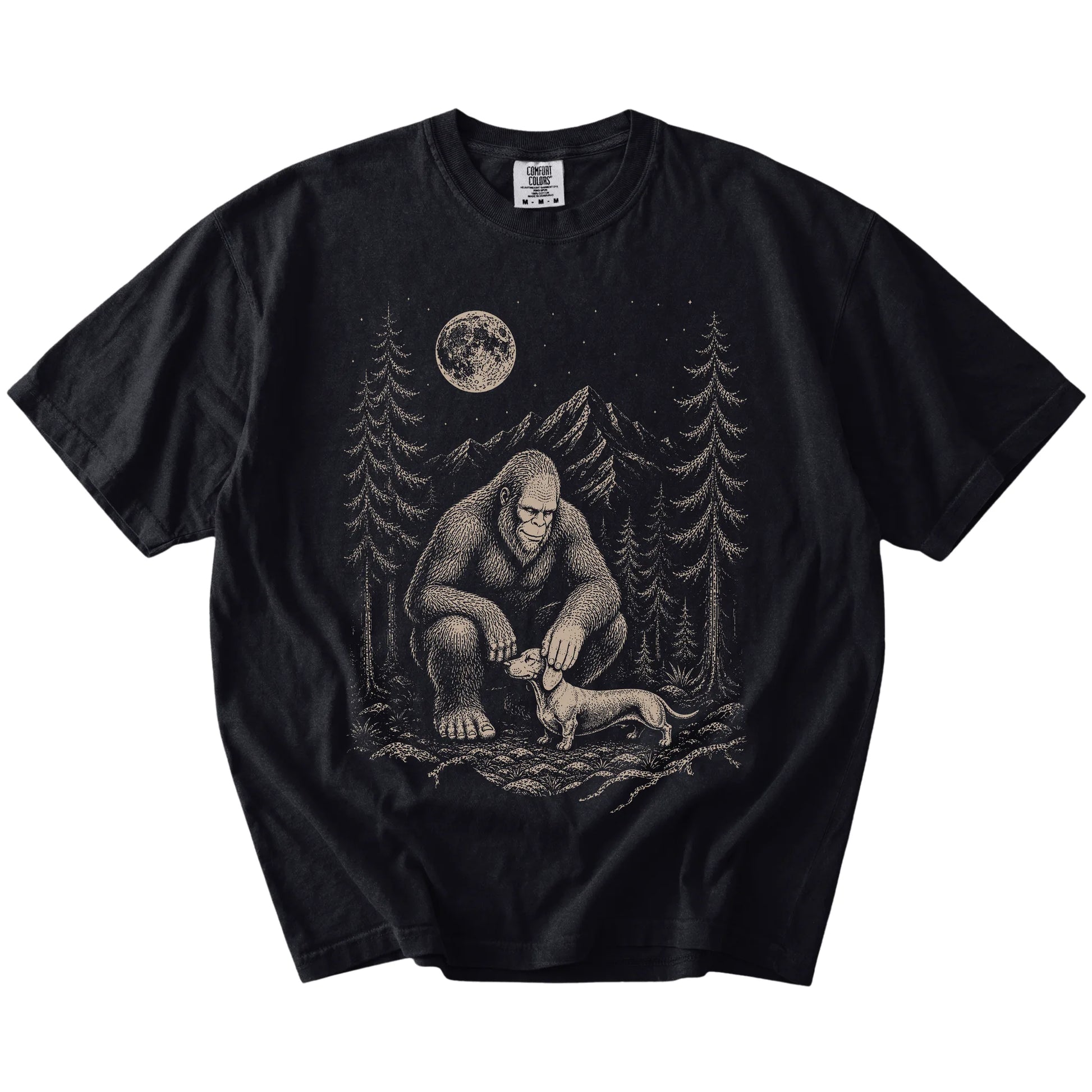 Bigfoot petting a Dachshund beneath the moon in a pine forest on a Black Comfort Colors® T-shirt