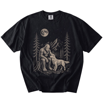 Bigfoot petting a Golden Retriever beneath the moon in a pine forest on a Black Comfort Colors® T-shirt