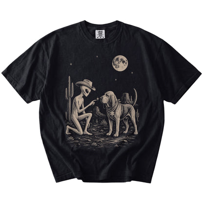 Cowboy alien fist-bumping a Bloodhound beneath the moon on a Black Comfort Colors® T-shirt