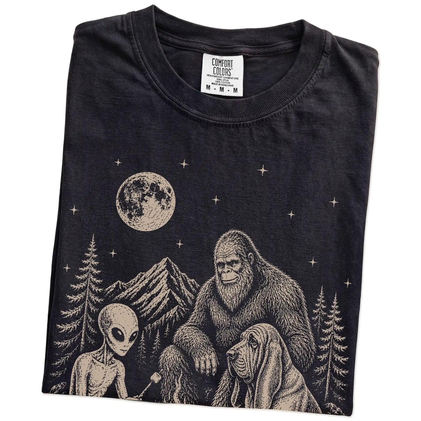 Folded Black Comfort Colors® T-shirt showing Bloodhound camping with Bigfoot and an alien