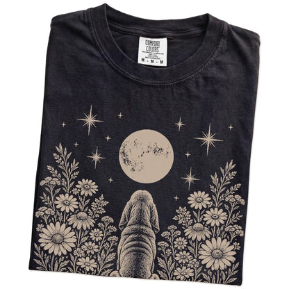Folded Black Comfort Colors® T-shirt showing Bloodhound beneath a wildflower moon