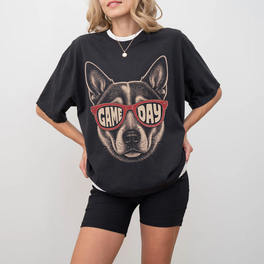 Model wearing a Black Comfort Colors® T-shirt with blue heeler wearing red game day sunglasses