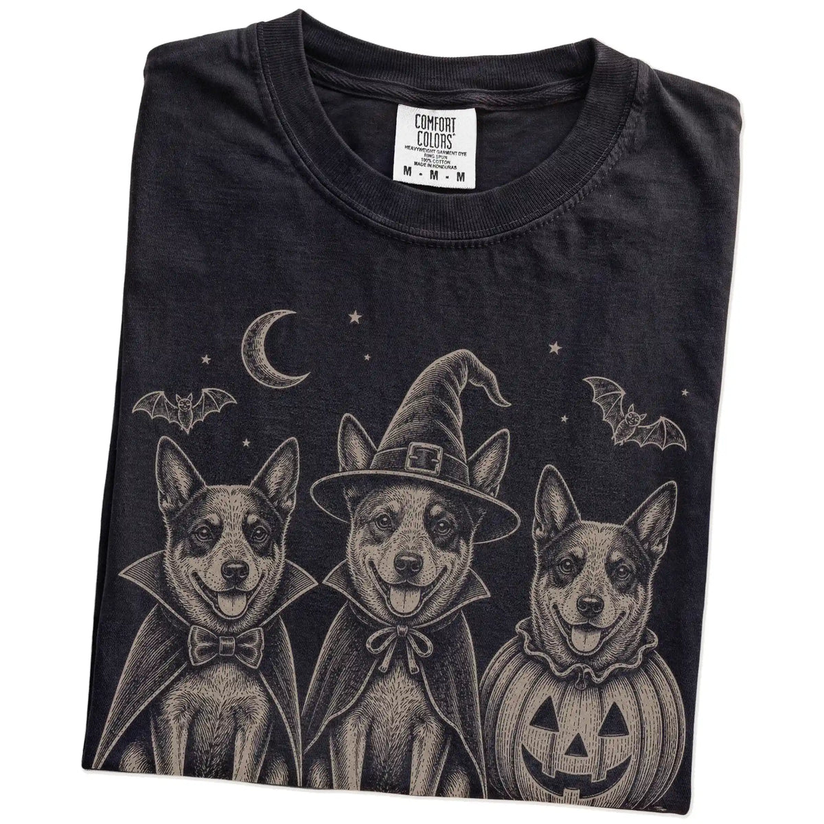 Folded Black Comfort Colors® T-shirt showing three Blue Heeler dogs dressed for Halloween beneath bats and a crescent moon
