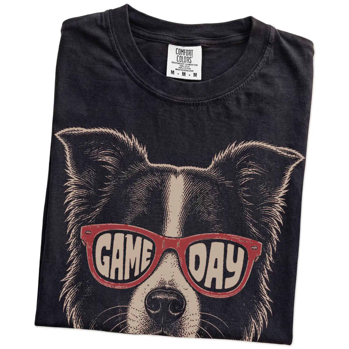 Folded Black Comfort Colors® T-shirt showing border collie wearing red game day sunglasses
