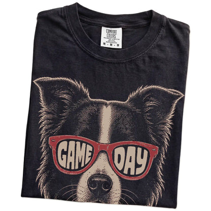 Folded Black Comfort Colors® T-shirt showing border collie wearing red game day sunglasses