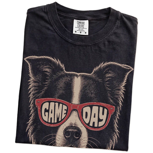 Folded Black Comfort Colors® T-shirt showing border collie wearing red game day sunglasses