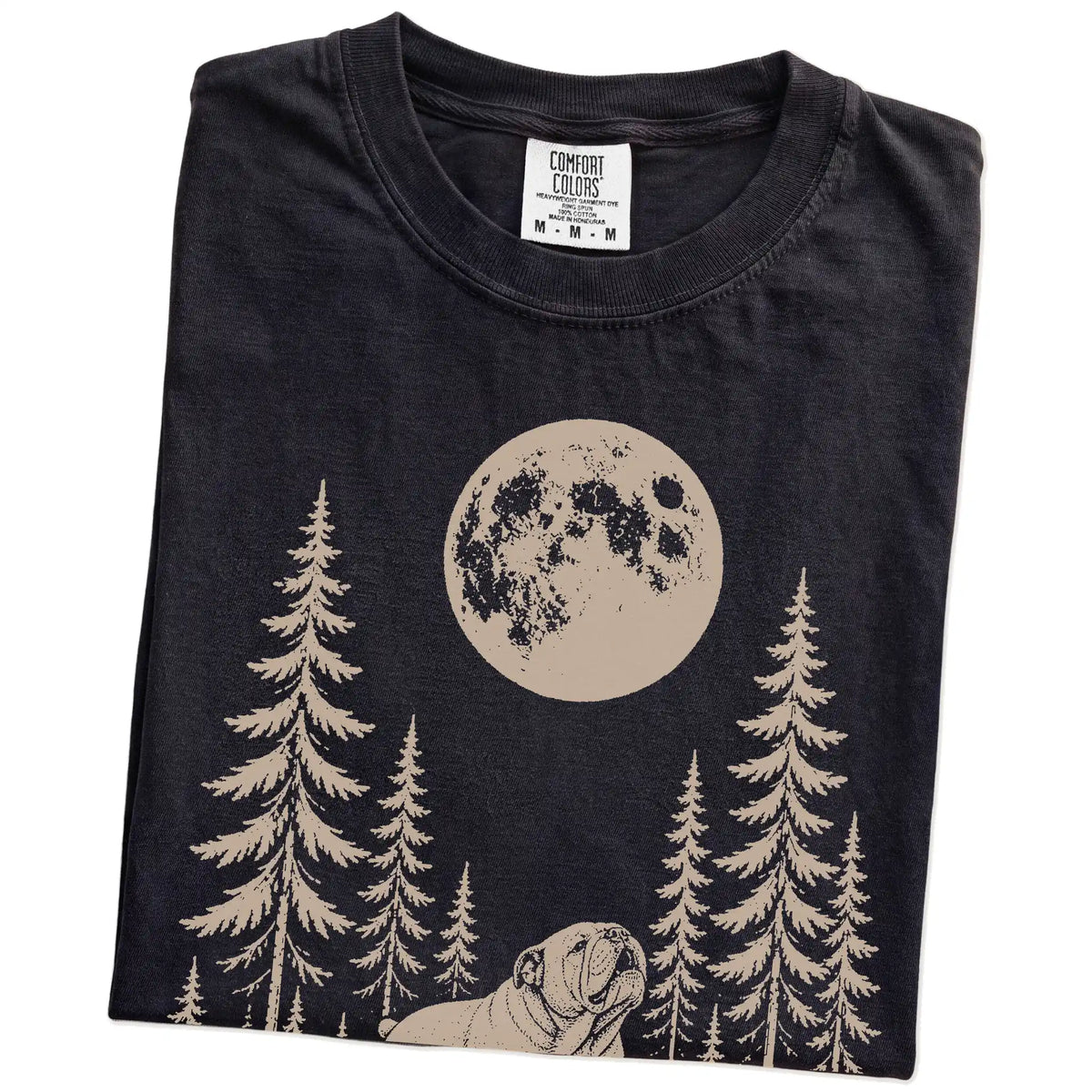 Folded Black Comfort Colors® T-shirt showing a Bulldog howling beneath the moon and pine trees