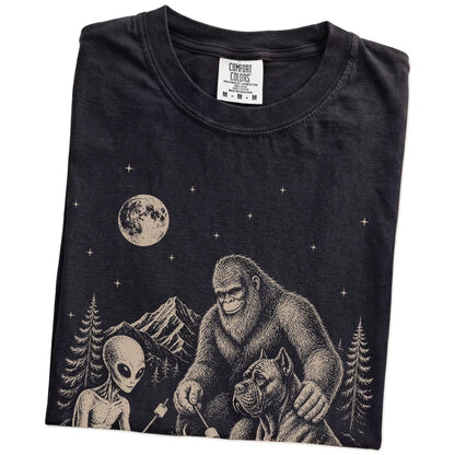 Folded Black Comfort Colors® T-shirt showing Cane Corso camping with Bigfoot and an alien