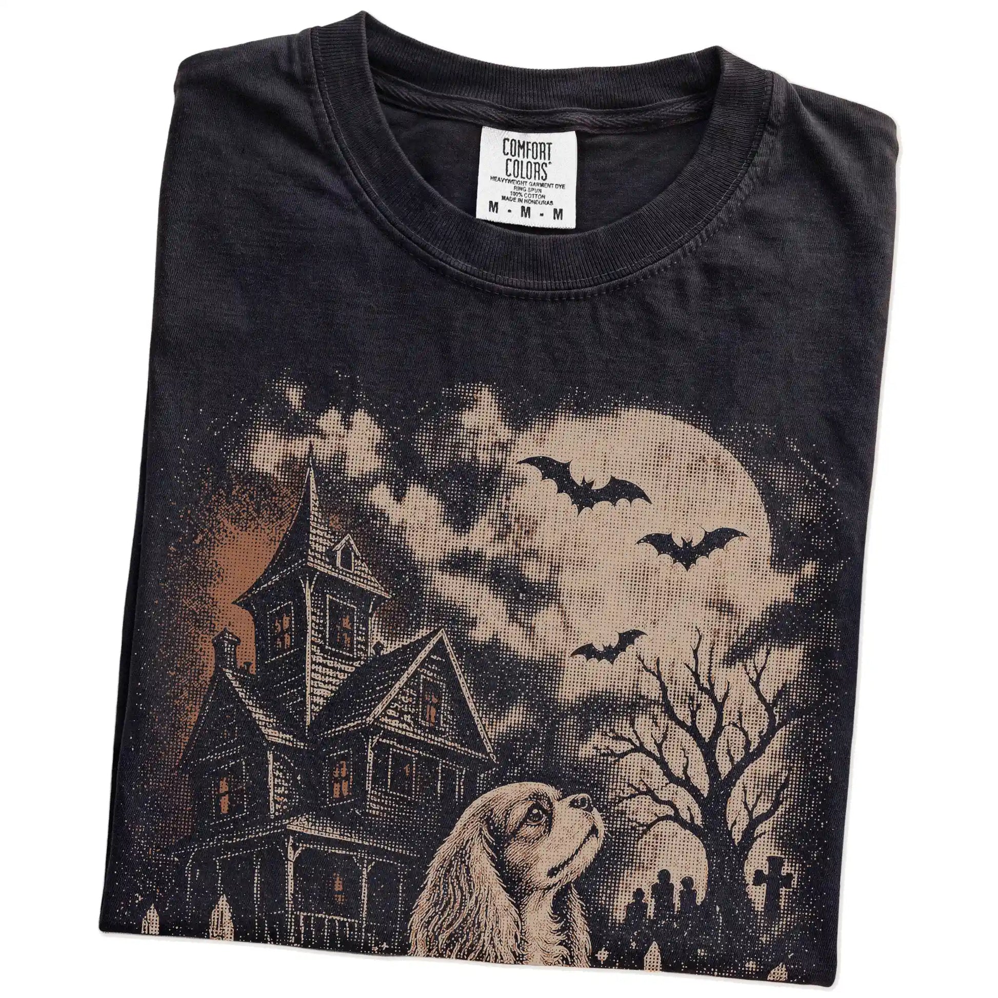 Folded Black Comfort Colors® T-shirt showing Cavalier King Charles Spaniel in a vintage haunted-house scene